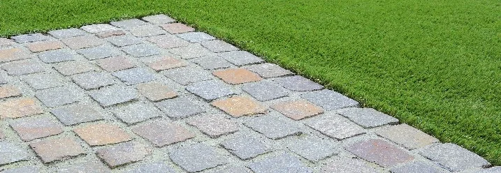 Pflasterweg neben grünem Rasen